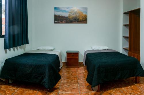a room with two beds and a picture on the wall at Hospedaje Gran Imperial in Tumbes