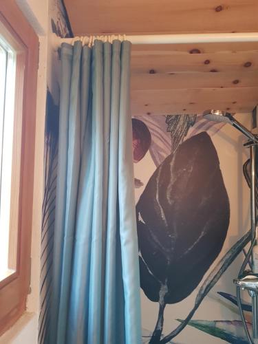 a blue curtain in a room with a lamp at Zirbenholz Tiny House "Waldhauszeit" am See in Mücke