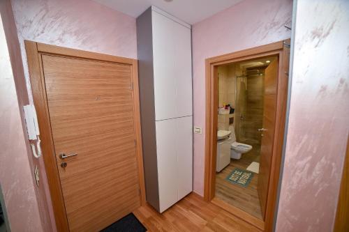 a bathroom with a wooden door and a toilet at Sunset Lux S3 Wellness & Spa Zlatibor in Zlatibor