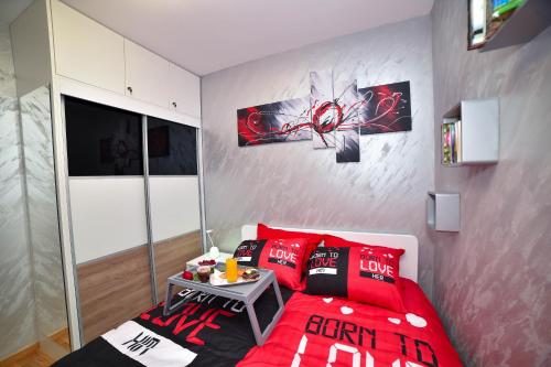 a bedroom with a red bed with red pillows at Sunset Lux S3 Wellness & Spa Zlatibor in Zlatibor