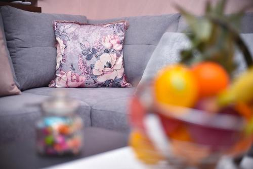 a couch with a pillow and oranges on a table at Sunset Lux S3 Wellness & Spa Zlatibor in Zlatibor