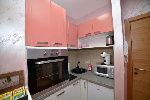 a small kitchen with pink cabinets and a microwave at Sunset Lux S3 Wellness & Spa Zlatibor in Zlatibor