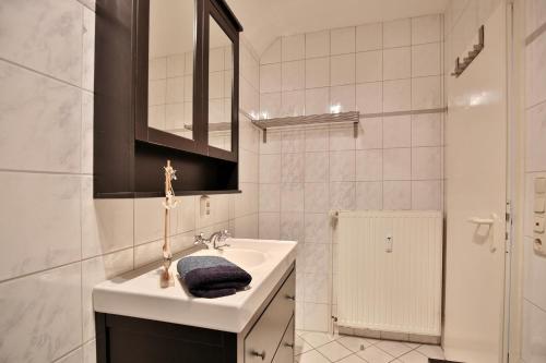 La salle de bains blanche est pourvue d'un lavabo et d'un miroir. dans l'établissement Maison Baltique Niendorf Ferienwohnung "Sonnendeck", à Niendorf