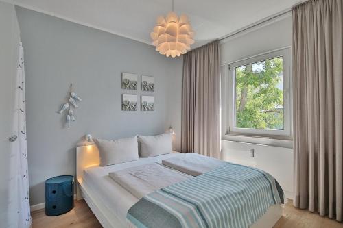 1 dormitorio con cama, ventana y lámpara de araña en Haus Strandallee 188 Schmuckkästchen, en Timmendorfer Strand