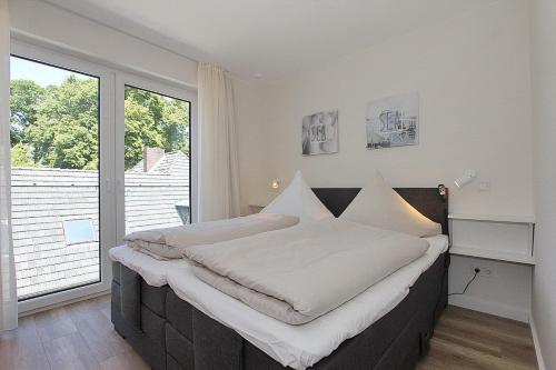 Bett in einem Zimmer mit einem großen Fenster in der Unterkunft Villa Stern Villa Stern Appartement 09 in Timmendorfer Strand