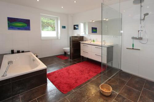 ein Badezimmer mit einer Badewanne, einer Dusche und einem roten Teppich in der Unterkunft Ferienhaus Gorch-Fock-Str 37 Ferienhaus Gorch-Fock-Str 37 in Timmendorfer Strand
