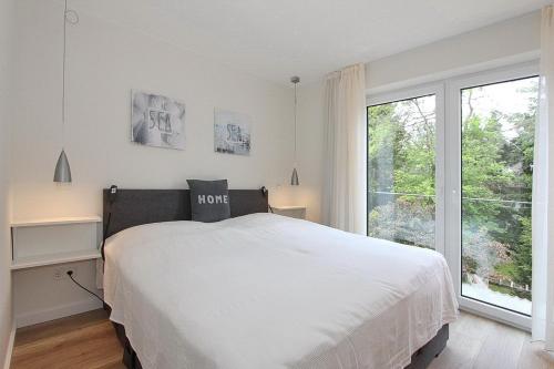 - une chambre avec un lit blanc et une grande fenêtre dans l'établissement Villa Stern Villa Stern Appartement 08, à Timmendorfer Strand