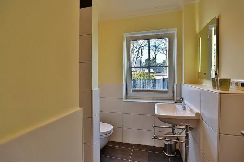 bagno con lavandino, servizi igienici e finestra di Baltic Sea Baltic Sea Appartement 1 a Niendorf