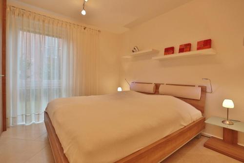- une chambre blanche avec un grand lit et une fenêtre dans l'établissement Wohldkamp 4 Wohldkamp 4 Appartement 04, à Timmendorfer Strand