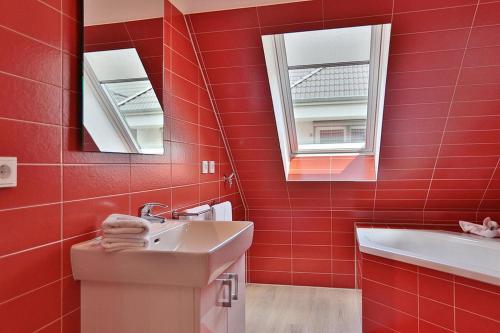 ein rotes Badezimmer mit einem Waschbecken und einem Spiegel in der Unterkunft Haus Bergstrasse 4 Haus Bergstraße 4 Appartement 9 in Timmendorfer Strand
