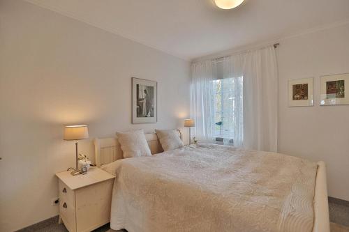 een witte slaapkamer met een groot bed en een raam bij Am Elchgrund, im Brook 9 Am Elchgrund Im Brook 9 Appartement 02 in Timmendorfer Strand