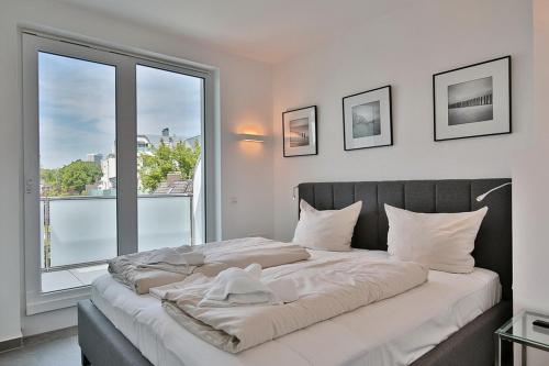 ein Schlafzimmer mit einem großen Bett mit einem großen Fenster in der Unterkunft Haus Wolburgstraße 1 Haus Wolburgstraße 1a Penthouse Haifisch Appartement 5 in Timmendorfer Strand