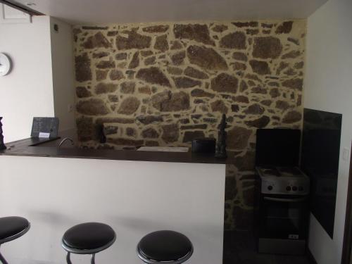 - une cuisine avec un mur en pierre, une cuisinière et des tabourets dans l'établissement La campagne au pied du MT ST MICHEL, à Roz-sur-Couesnon