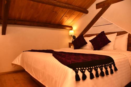 a bedroom with a white bed with black pillows at Hotel Junvay in San Cristóbal de Las Casas