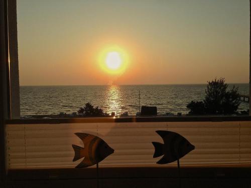 a view of the sunset from a window with umbrellas at Feriendomizil Strandblick Feriendomizil Strandblick Appartement 1 MeerBlick in Haffkrug