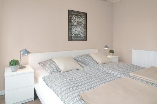 Dormitorio blanco con cama con manta a rayas en Kurparkresidenz Kurparkresidenz Appartement 13, en Scharbeutz