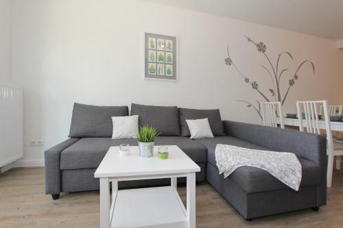 a living room with a gray couch and a white table at Kurparkresidenz Kurparkresidenz Appartement 11 in Scharbeutz