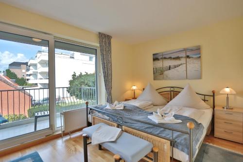 um quarto com uma cama e uma grande janela em Strandschlößchen Strandschlösschen Appartement 24 em Haffkrug