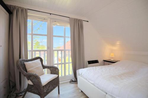 a bedroom with a bed and a chair and a window at Ferienhaus Seeweg 1 Ferienhaus Seeweg 1 in Klingberg