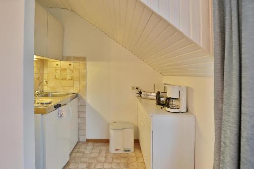 una pequeña cocina con armarios blancos y una escalera en Appartemenhaus Linda-Lu Appartementhaus Linda-Lu Appartement 7, en Scharbeutz