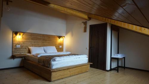 卡茲別吉的住宿－Mansarda Kazbegi，一间卧室配有一张大床和木制床头板