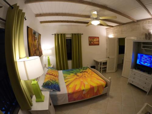 a bedroom with a bed and a flat screen tv at Yellow Bird Apartment in Christ Church