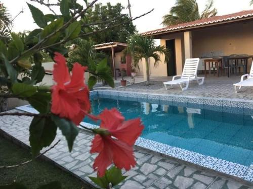 a swimming pool with red flowers in front of a house at Pousada Vale Encantado in Serra de São Bento