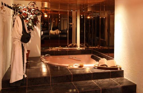 a bathroom with a bath tub and a large mirror at Auberge Godard in Nominingue