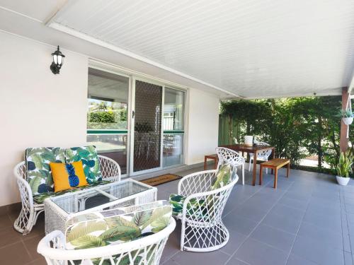 un porche avec des chaises en osier blanc et une table dans l'établissement Happy Dayz - Pet Friendly - Walk to Dog Beach, Restaurants & Playgrounds, à Gold Coast