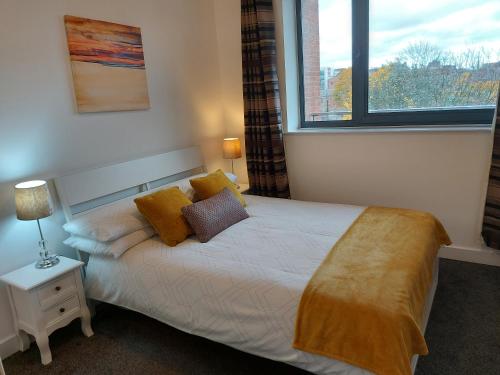 ein Schlafzimmer mit einem Bett mit gelber Bettwäsche und einem Fenster in der Unterkunft Large 2 Bed, 2 Bath, Free Parking & WiFi in Sheffield