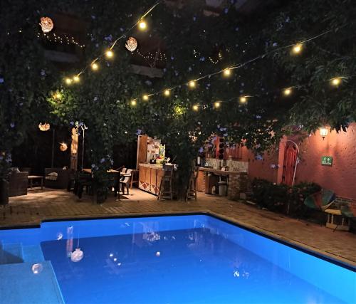 een blauw zwembad in een tuin met verlichting bij Hotel Casa de Verano - Solo adultos - in Santa Fe de Antioquia