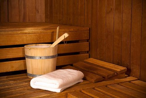 a wooden sauna with a bucket and a towel at nestor Hotel Stuttgart-Ludwigsburg in Ludwigsburg