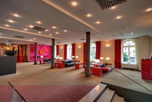 a large room with columns and red furniture in a building at nestor Hotel Stuttgart-Ludwigsburg in Ludwigsburg