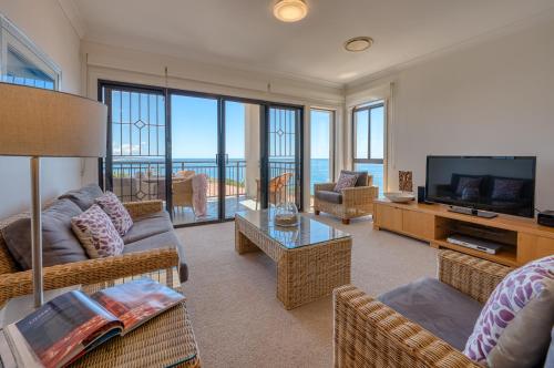 a living room with couches and a television with a view at The Point Coolum in Coolum Beach