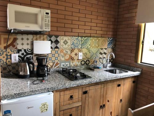 een keuken met een wastafel en een magnetron bij Moradas Brisa da Lagoa in Imbituba