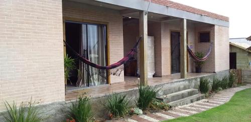 une maison avec une terrasse couverte dotée de hamacs. dans l'établissement Moradas Brisa da Lagoa, à Imbituba