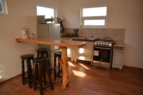 a kitchen with a wooden table and some bar stools at Cabañas Pidén in Punta Arenas