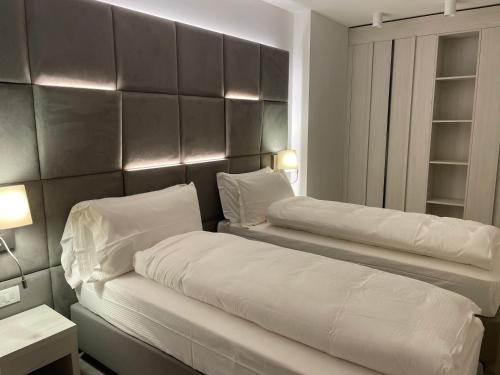 a bedroom with two beds with white pillows at ROSENSUITE La Residenza del rosengarten in Pinzolo