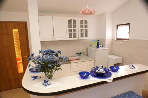 eine Küche mit blauen Schalen und Blumen auf der Theke in der Unterkunft Apartments Mari - amazing sea view in Prizba