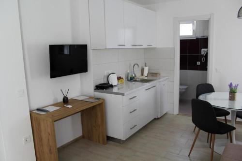 eine Küche mit weißen Schränken, einem Tisch und einem Esszimmer in der Unterkunft Royal Apartmani in Banja Luka