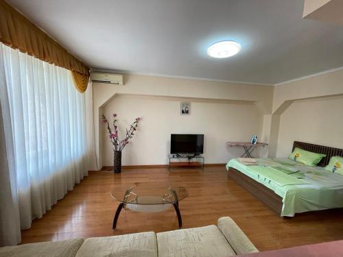 salon z łóżkiem i telewizorem w obiekcie Квартира w mieście Ałma-Ata