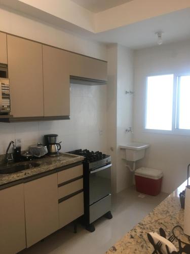 eine Küche mit Herd oberer Ofen neben einer Spüle in der Unterkunft Apartamento Bertioga Torres in Bertioga
