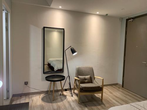 a bedroom with a chair and a mirror and a lamp at K Hotel in Kota Kinabalu