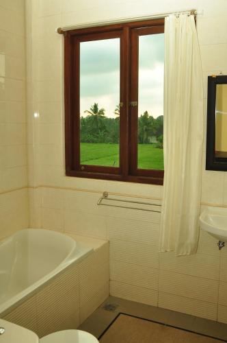 a bathroom with a tub and a sink and a window at Three Dewi's Guest House in Ubud