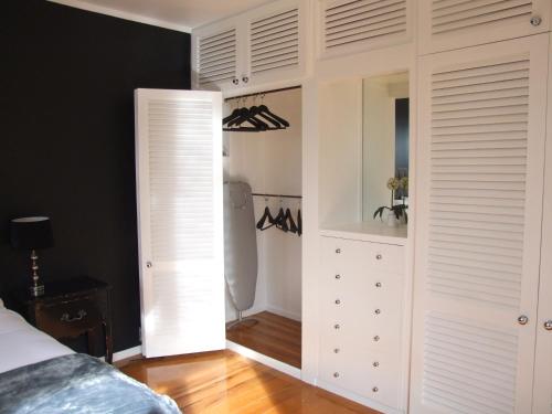 1 dormitorio con armarios blancos y armario en The Quiet Quarter, en Auckland