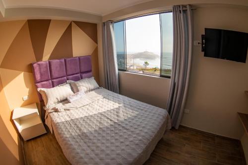 巴蘭卡的住宿－Besso Beach Hotel，一间卧室配有一张带紫色床头板的床和窗户。