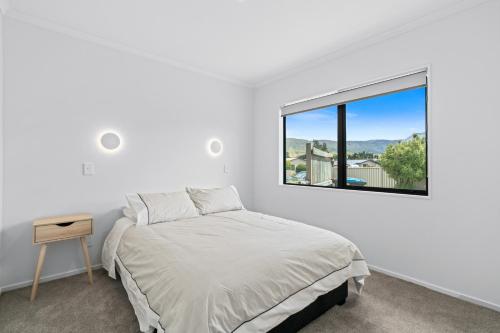 a white bedroom with a bed and a window at Cromwell Charmer - Cromwell Holiday Home in Cromwell