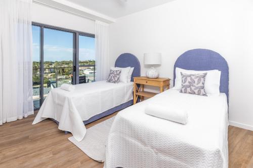 two beds in a room with a window at The Waterford Prestige Apartments in Caloundra