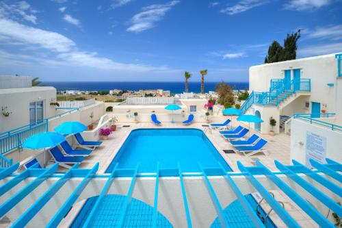a swimming pool with blue chairs and umbrellas at Sunny Hill Hotel Apartments in Paphos
