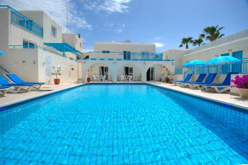 a large swimming pool with blue chairs and a building at Sunny Hill Hotel Apartments in Paphos City